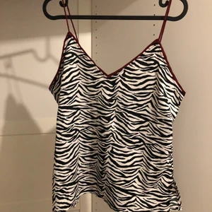 Zebra linne - Oanvänt linne från BIKBOK. Zebra mönstrat med röda detaljer. Storlek S men skulle säga att den passar nog M/L också då den sitter ganska löst. Frakt 45kr.