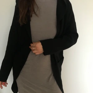 Svart fin stickad kofta med luva - En jättefin tjock svart stickad kofta med luva i jättebra skick. Storlek onesize men jag är en storlek small och den sitter fint på mig.