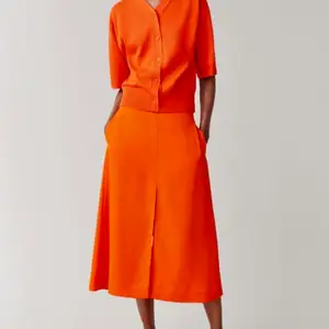 Längre kjol i riktigt cool orange färg med slits från COS! Helt ny och lappen sitter kvar! Nypris 690kr. 