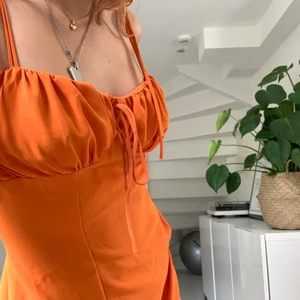 Orange klänning - Säljer denna superfina klänning som man kan knyta i ryggen så att den sitter perfekt i midjan. Endast använd en gång! Budgivning vid många intresserade!