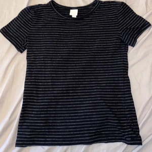 Randig t-shirt  - En svart t-shirt med tunna vita linjer. Kanppt använd. Nyskick . 50kr + 48kr frakt 