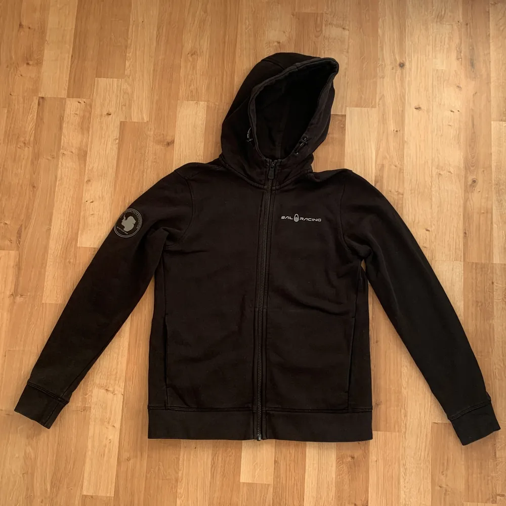 Sail Racing zip hoodie (Antarctica Zip Hood Carbon) i svart färg. Är i storleken 170 men passar också S. Den är i bra/mycket bra skick och köparen står för frakten.. Hoodies.