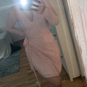 PLISSE WRAP DRESS NLY - Plisse wrap dress från Nelly. Bara använd nu när jag tog kort. Tyvärr sprucken i ärmen ( var så när jag fick den) bara att sy. Ljusrosa väldigt gullig