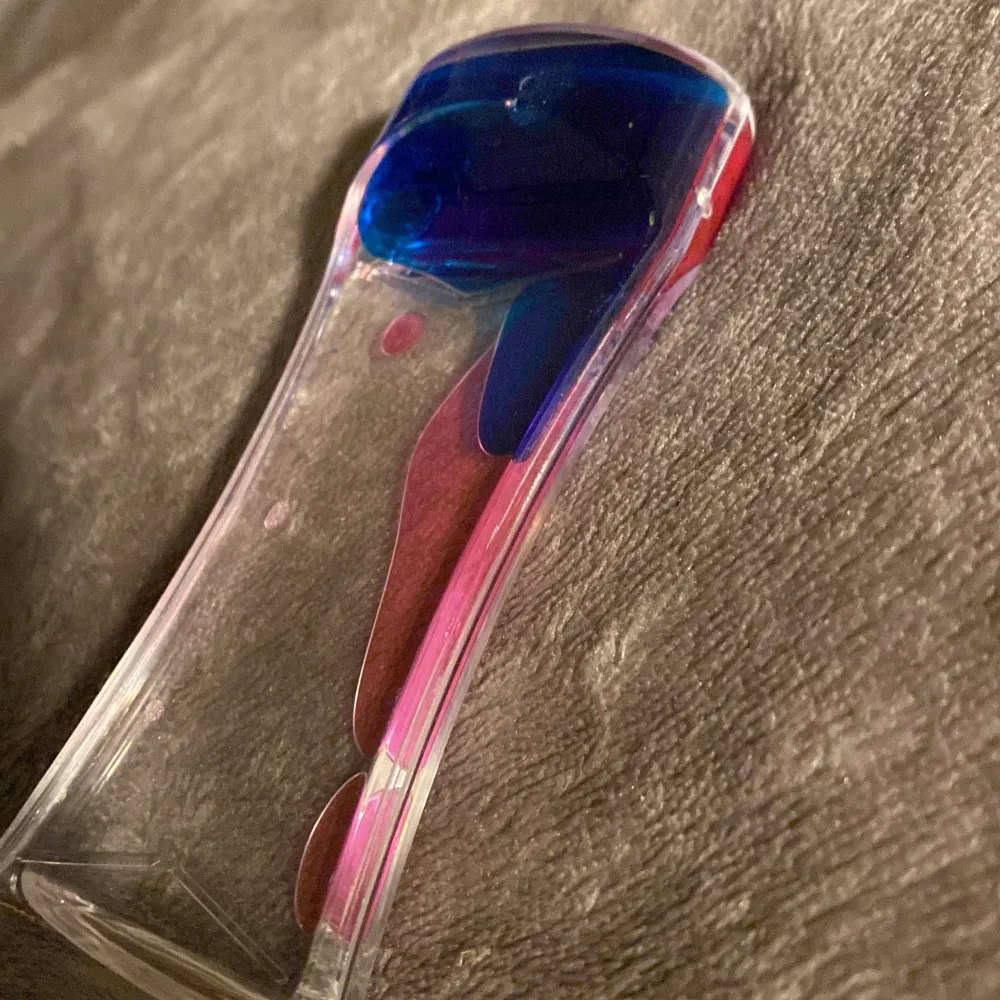 Ett glas förpackning med rosa och blå olja ish i.. Muu.