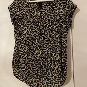 Leopardmönstrad t-shirt från only - En leopardmönstrad t-shirt från only. Stor i storleken så passar en M/ 38. Är en kort dragkedja på ryggen