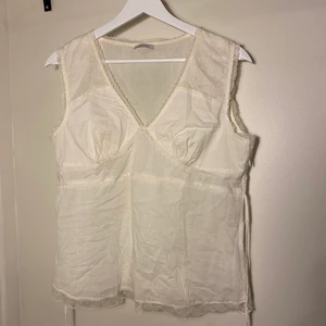 Vit topp i linne med spetsdetaljer - En väldigt fin linnetopp med spetsdetaljer och snörning i midjan.