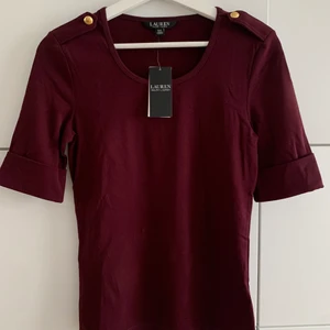 Ralph Lauren topp - Superfin Ralph Lauren (Topp Erick Elbow Sleeve Knit) Kort ärm med uppvik • Rund hals • Axelklaffar med guldfärgade knappar • Gjord av bomullstrikå  Aldrig använd & prislapp kvar.  Storlek S.