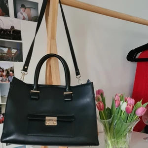 Handväska i läderimitation - Läcker handväska/portfölj med avtagbart axelband 🖤🌟 Guldfärgade detaljer, en ytterficka, tre innerfickor (varav en med dragkedja) och hela väskan kan stängas med dragkedja. 💕 Tyvärr har den förlorat formen lite, och kan inte för tillfället stå upp själv (se bild 3), men när det är saker i väskan står den bra ändå! Köpt på HM år 2012 för 250kr🤗