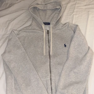 Grå Ralph Lauren tröja med dragskeddja  - Grå Ralph Lauren tröja med dragskeddja. Vita snören använder aldrig nyköpt 1500 säljer för 500 ink frakt inga fläckar och smuts helt ren passar både M/S skit fin😊 skriv om du e intresserad🥰