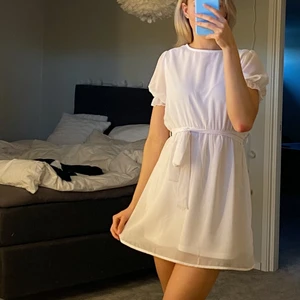 Vit kort klänning - Jättesöt kortärmad kort klänning från NA-KD som endast använts en gång. Mycket fint skick. Ej genomskinlig, tunnare material i ärmarna 🌸 avtagbart snöre runt midjan och försluts med knapp i ryggen (bild 2) 🌸 kontakta mig för frågor / fler bilder!