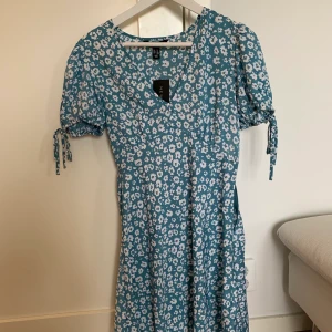 Blommig klänning  - Aldrig använd så har fortfarande lappen kvar. Jättefin och perfekt till sommaren:))