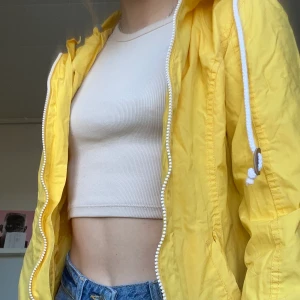 Klassisk gul regnjacka - Jättefin gul regnjacka som tyvärr inte längre kommer tillanvändning. Lagom lång. Strl 34. Smal i ärmarna.