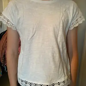 En vit t-shirt i strl 146/152 med fina detaljer i alla kanter. Detaljerna är som ett blommigt mönster, skönt material att ha när du vill. frakt ingår. Tvättar såklart innan frakt.