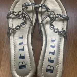 Guld sandaler från Belle - Sandaler i guld färg från Belle. I bra skick. Storlek 36. Hämtas på Kungsholmen i Stockholm alt skickas mot frakt