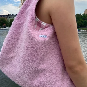 Handsydd rosa handväska i frotté  - Perfekt strandväska i rosa frotté och rosa-rutig bomullstyg. Väskan går att vändas ut och in så det är 2in1. Den rutiga sidan har två djupa fickor perfekt för vattenflaskan, solglasögonen, plånboken etc. (Fler bilder på formen finns i min profil där jag även säljer en gul variation) 