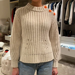 Zadig Voltaire tröja - Krämvit stickad tröja med orange coola knappar som detalj. Är inprincip aldrig använd. Nypris 3295 men säljer för 1500kr. Sjukt snygg till sena sommarkvällar!
