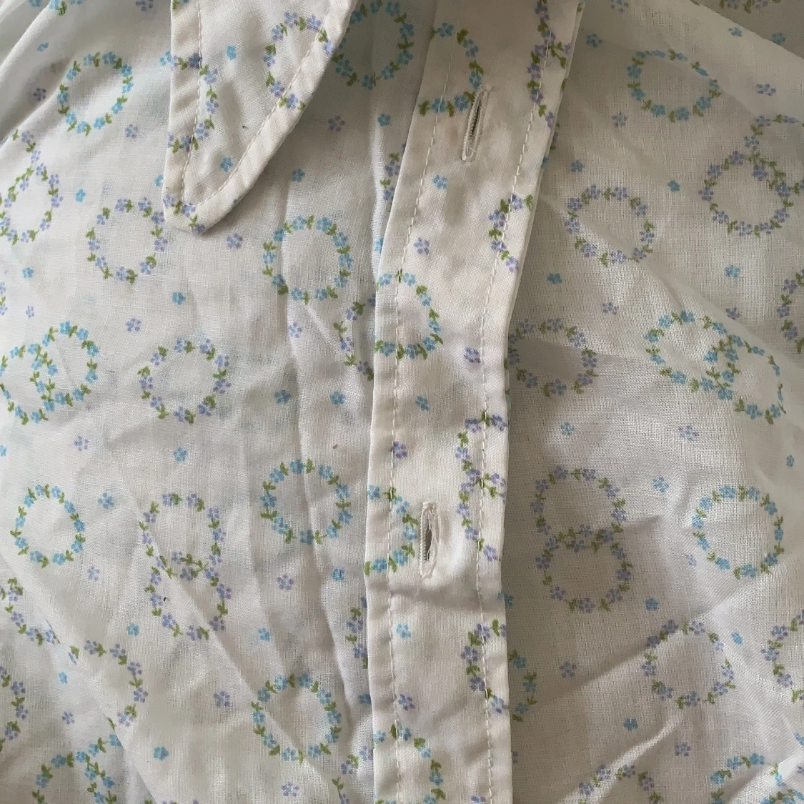 Vit skjorta med blå små blommor och gröna löv.  - 91