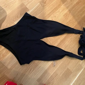 Svart baddräkt i strl. M - Jättefin svart baddräkt. Helt ny med trosskydd kvar. Går att knyta i nacken exakt så inspänt du vill ha den. Öppen i ryggen