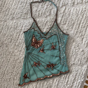 Y2K Halterneck fjärilstopp - Säljer den här helt sjuka lite genomskinliga halternecktoppen! den är öppen i ryggen och sitter som en smäck! Det är en del pärlor som har trillat av på framsidan. Tveka inte på att höra av er vid fler frågor🧚🏼‍♂️ (OBS! tänk på att bud är bindande) 