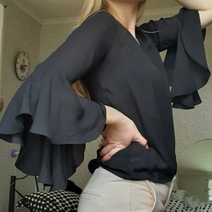 Volangblus nakd strl 34 - Blus med volangärmar, storlek 34 från NA-KD. Knytning bak i nacken. Blusen har en liten missfärgning, kontakta mig för bilder. Säljer då den inte kommer till användning. 60 kr + frakt <3