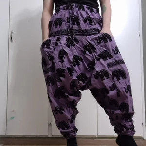 Haremsbyxor med elefanter. - Lila haremsbyxor med svarta elefanter på. Har lite blå akrylfärg vid midjan tyvärr men annars i god skick. Small size.