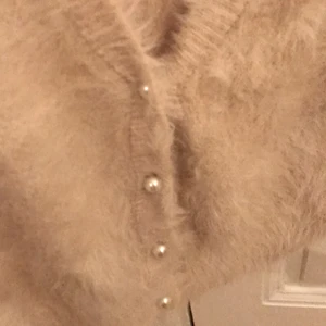 Stickad kofta - En stickad kofta med kort ärm från Lindex, stl S. Köparen betalar frakt ä, ansvarar inte för postens slarv. Oanvänd. Beige, mjukt material.