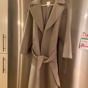 HM kappa - Säljer nu min oanvända, fina gråa kappa från HM, den är i storlek S och jag är 164 och den slutar vid mina smalben ungefär