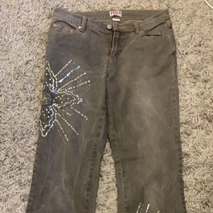Lågmidjade jeans gråa - Ett par fina gråa lågmidjade jeans med palijett detaljer. Köpta second hand. De är endast använda ett fåtal gånger. Jag är 167 cm lång och de går ner till mina anklar. Skulle säga att de passar S/M. 100kr + frakt