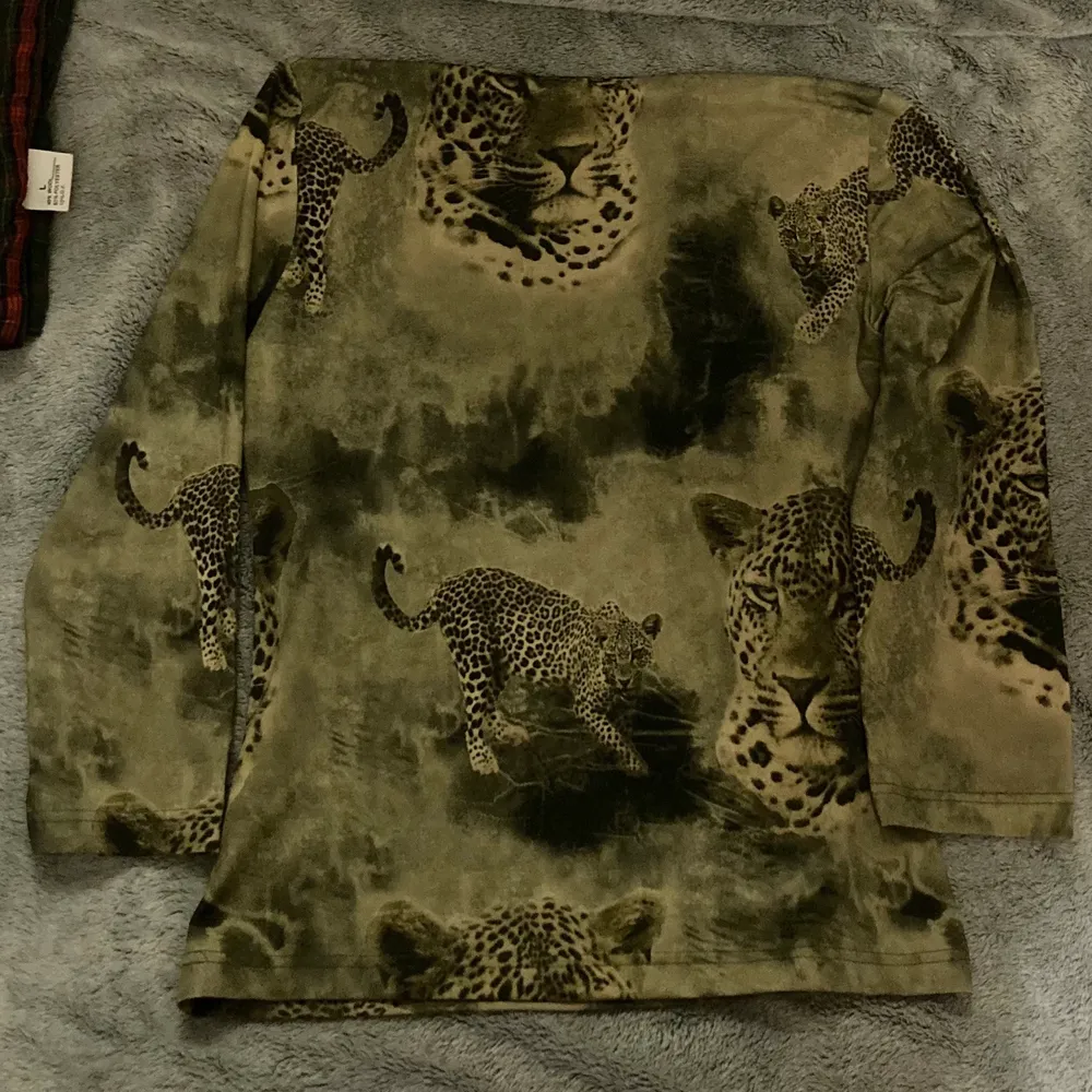 Grön tröja i stretchigt syntetiskt tyg. Grönt tryck med leoparder på. Fint skick. Strl M :). Toppar.