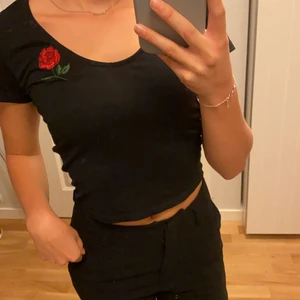 Croppad T-shirt - En svart söt kroppad T-shirt med en röd ros broderad🌹