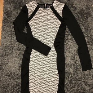 Klänning  - Svart och vit mönstrad klänning. Kroppad. Tight runt armarna 