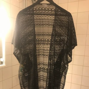 Spetskimono - En snygg och sexig spets/nät kimono i svart med fransdetaljer längst ner som passar både dag som kväll.