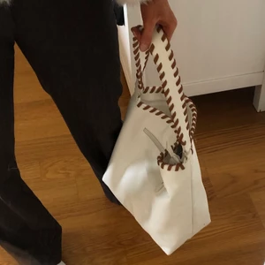 vit och brun väska - Säljer denna rymliga väska i läderimitation som jag tyvärr inte minns vart den kommer ifrån🤎🪐🤍