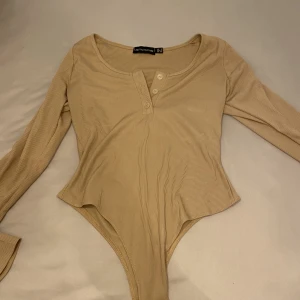 Body pretty little thing - Ribbad beige body från pretty little thing. Storlek 36 aldrig använd 