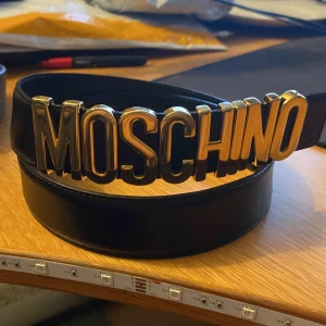 Moschino bälte - Moschino bälte i fina skick, bältet är 90 cm långt och är i riktigt läder. Skriv så svarar jag på era frågor så snabbt jag kan.