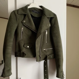 Jacka från Zara - Jacka från Zara i mocka material. Färgen är i militärgrön. Jackan har flera fickor och har bälte runt midjan!💕