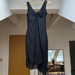 Svart Klänning - Fin lite asymmetrisk cocktailklänning med snörad rygg. Jag är en storlek S och den passar mig bra/aningen tajt