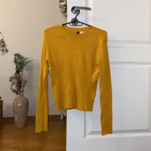 Söt gul/orange långärmad , stretchig tröja från H&M. Storlek M. Använd några gånger, men fortfarande i bra skick. Säljs pga att den ej används längre. Köparen står för frakten! 