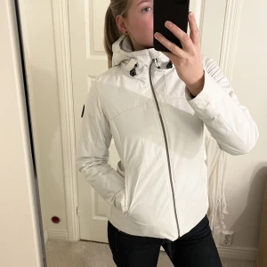 Vit skidjacka - Vit fodrad skidjacka från Everest i storlek S. Den har använts två skidresor och har fått några slitningar som man kan se på bild 3, finns små sånna slitningar på lite olika ställen på jackan. Päls till luvan finns även att sätta på om man vill. 