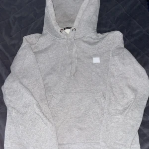 Acne FERRIS face hoddie  - Det är en grå hoodie från acne studios i et helt okej skick. Lite sliten på en ärmen som man ser på bilden. Nypris 2000kr Köparen står för frakt 