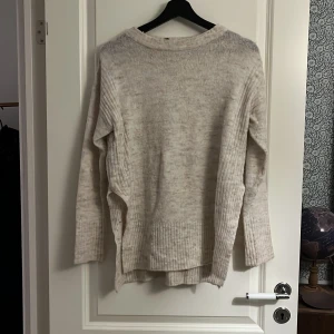 Stickad tröja  - Beige stickad tröja från HM. Slits på båda sidorna, aningens längre baktill än framtill. 