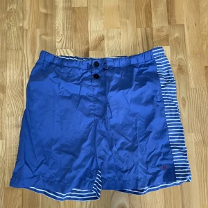 Stone Island Marina badbyxor  - Riktigt feta badbyxor från Stone island Marina i fint skick. Helblåa på framsidan och randiga på baksidan med Stone island loggan. Funkar som shorts också. 
