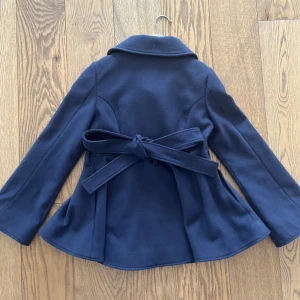 Kappa Sthlmstil Blå - Perfekt vår/höst kappa, passar barn mellan 8-10 år tyvärr har jag växt ur denna otroligt fina kappa. Fint skick.