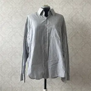 en vit/blå randig skjorta i oversize fit. 