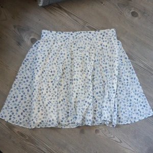 Kort kjol oanvänd - Vit kjol med blåa blommor. Helt oanvänd med lappen kvar. 