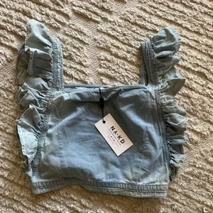 Topp - Superfin topp i ljusblå denim från NA-KD💖 aldrig använd- prislappen sitter kvar!! I storlek M!