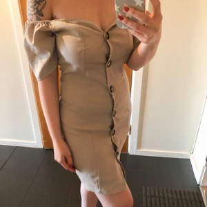 Offshoulder-klänning  - Beige offshoulder-klänning med knappar från boohoo, storlek UK10 (38). Aldrig använd, lappar kvar. 