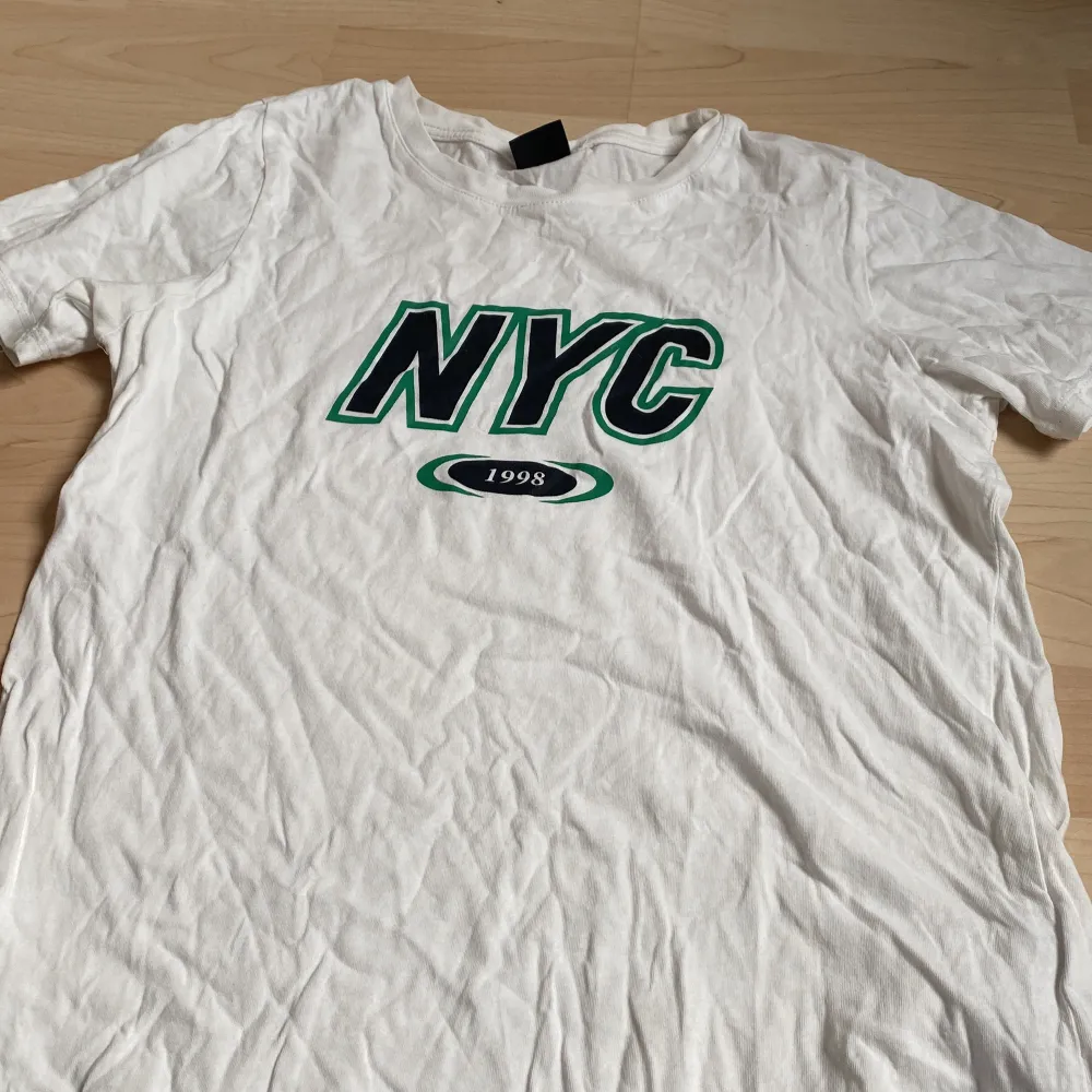En vit tröja med svart text på och gröna detaljer . T-shirts.