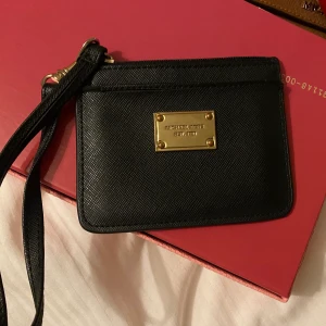Michael Kors - Äkta Michael Kors korthållare.  Har även dragkedja upptill med rätt så rymligt fack.   Denna är använd men tagits väl hand om.