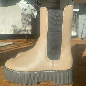 Höga boots, beige, 38 - Säljer dessa helt nya trendiga bootsen på grund av för liten storlek. Oanvända och endast bara provade inomhus en gång.   Skön passform och lätt att ta på sig. Hög sula.  Färg: Beige Storlek: 38 Matrial: Fakeläder  